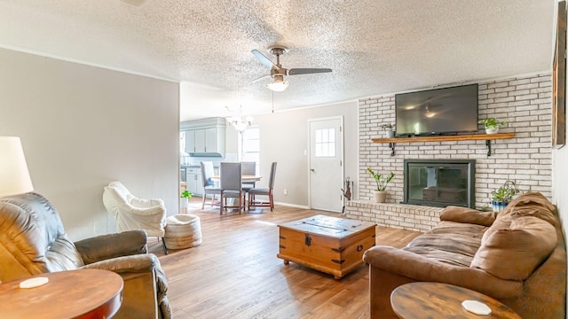 living room with a textured ceiling, ceiling fan, light hardwood / wood-style flooring, and a brick fireplace