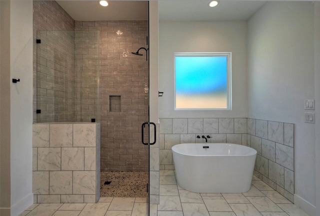 bathroom featuring tile walls and separate shower and tub