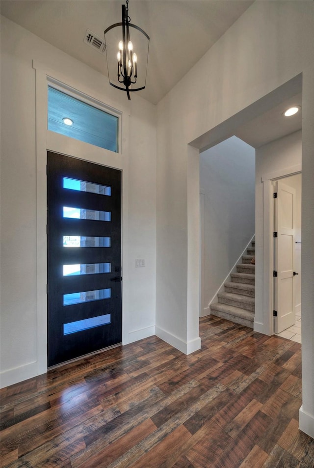 foyer entrance with dark wood-type flooring and a notable chandelier