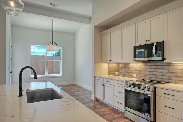 kitchen with stainless steel appliances, light stone countertops, sink, and white cabinets