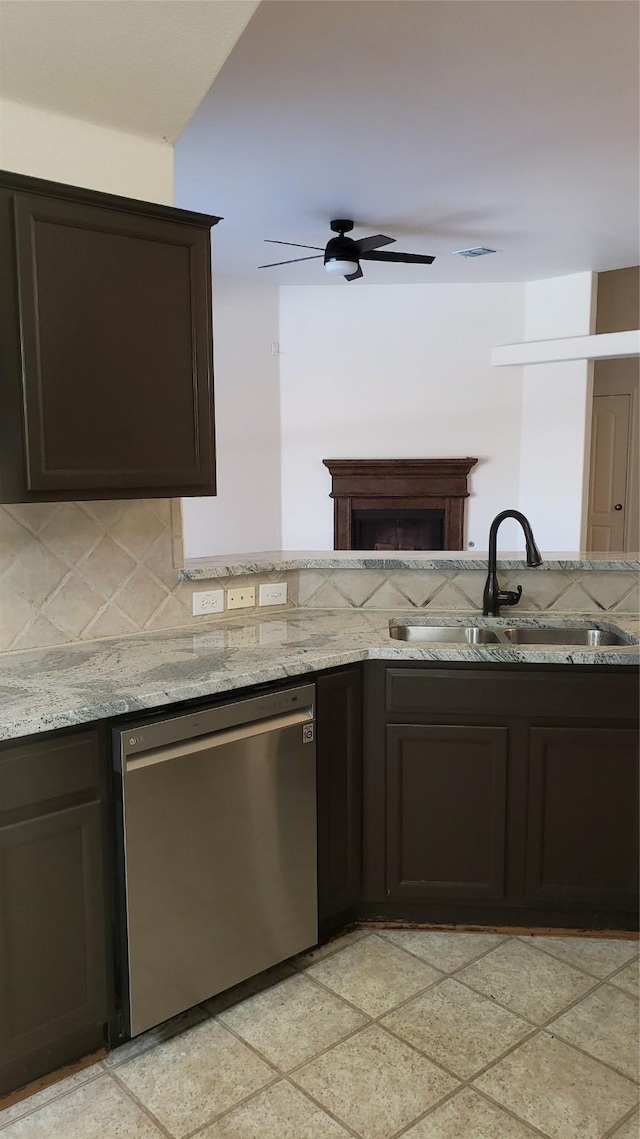 kitchen featuring dishwasher, backsplash, sink, light stone countertops, and dark brown cabinets