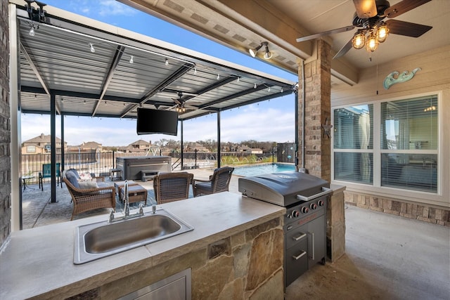 view of patio / terrace featuring a hot tub, ceiling fan, a sink, fence, and exterior kitchen