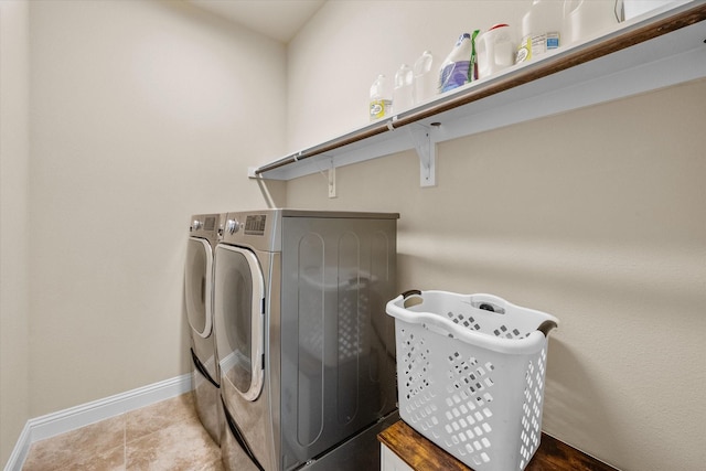 clothes washing area with washer and dryer, laundry area, baseboards, and tile patterned floors