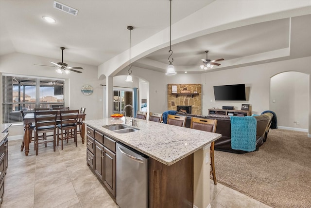 kitchen featuring arched walkways, pendant lighting, a sink, and an island with sink