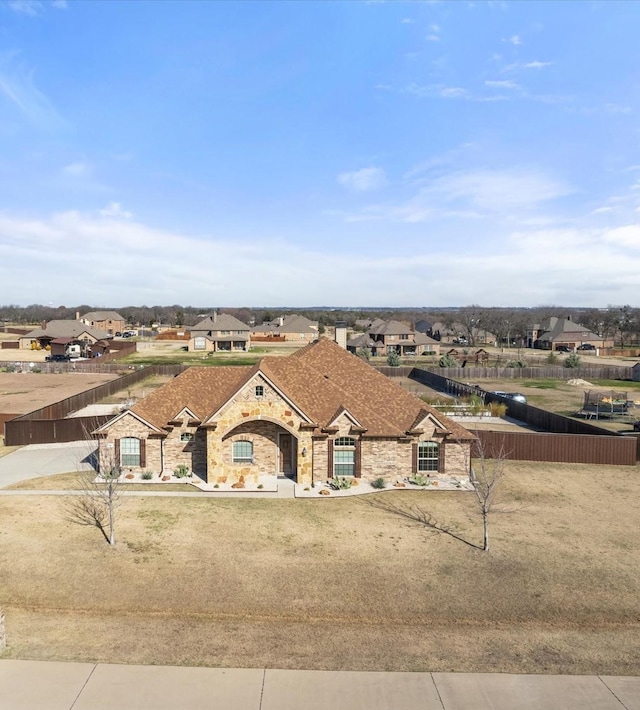 view of front of house featuring a residential view, stone siding, and fence