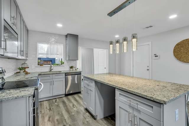 kitchen featuring gray cabinetry, a center island, sink, appliances with stainless steel finishes, and decorative light fixtures