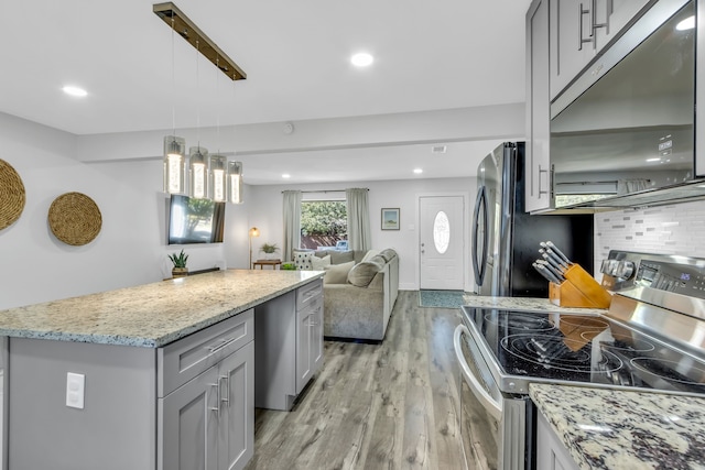 kitchen with backsplash, stainless steel appliances, light hardwood / wood-style flooring, gray cabinets, and hanging light fixtures