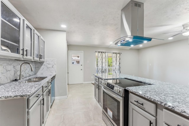 kitchen with island exhaust hood, light stone countertops, stainless steel appliances, sink, and gray cabinets