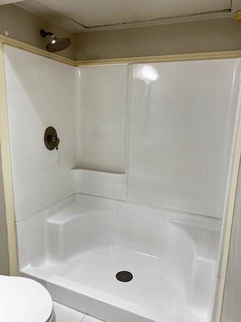 bathroom featuring a shower, tile patterned flooring, and toilet