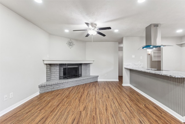 unfurnished living room with ceiling fan, a fireplace, wood-type flooring, and a textured ceiling