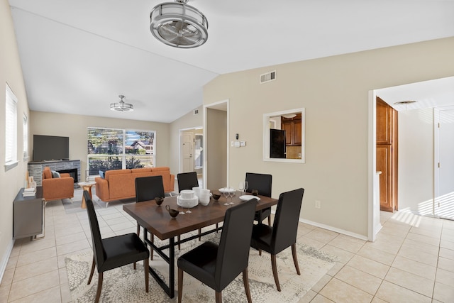 dining room with a fireplace, lofted ceiling, and light tile patterned flooring