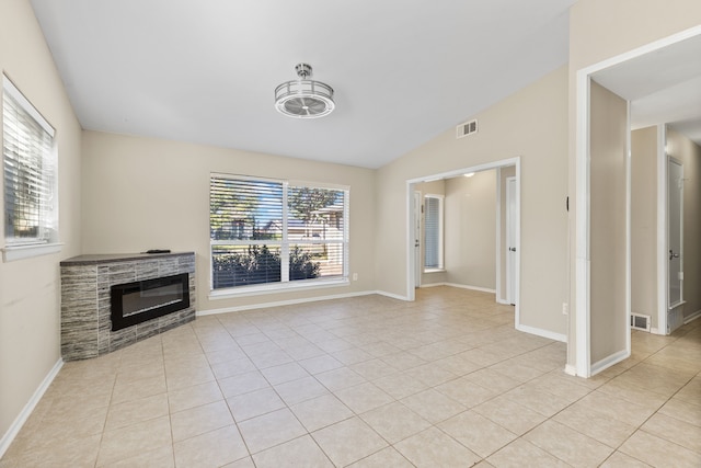 unfurnished living room featuring plenty of natural light, a fireplace, light tile patterned flooring, and lofted ceiling