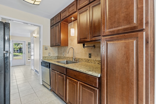 kitchen with sink, light stone counters, stainless steel dishwasher, black refrigerator, and light tile patterned flooring