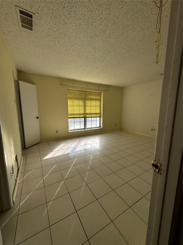 tiled empty room featuring a textured ceiling