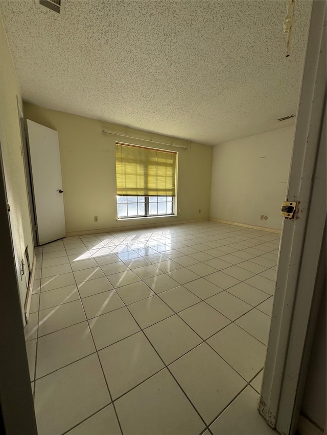 tiled empty room with a textured ceiling