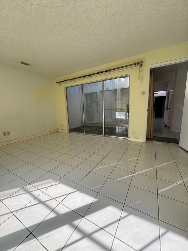 tiled empty room featuring a textured ceiling