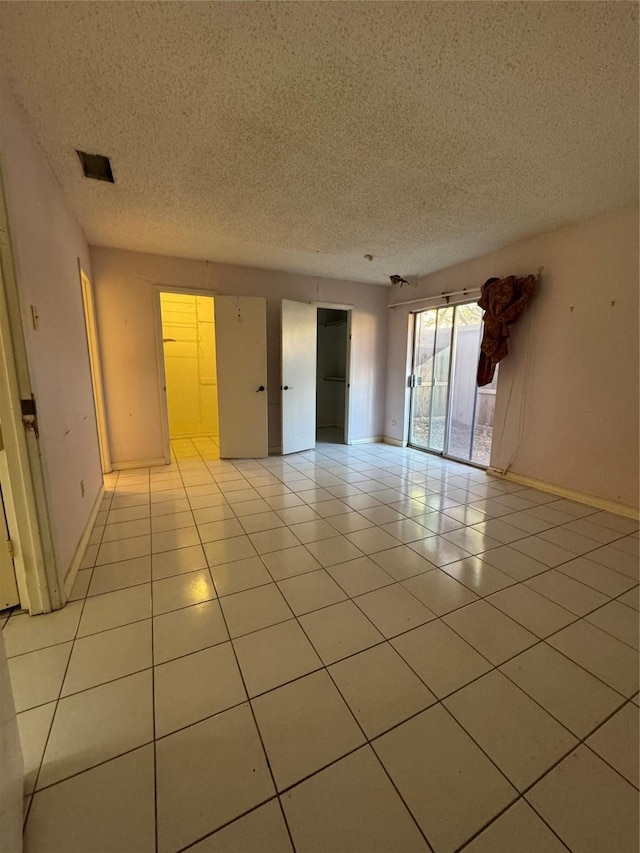 tiled empty room with a textured ceiling