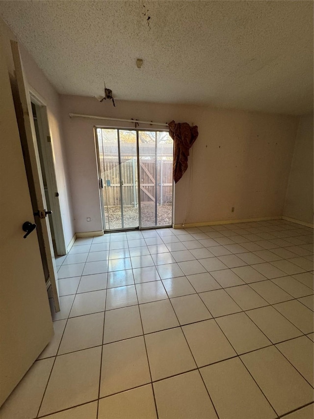 spare room featuring light tile patterned flooring and a textured ceiling