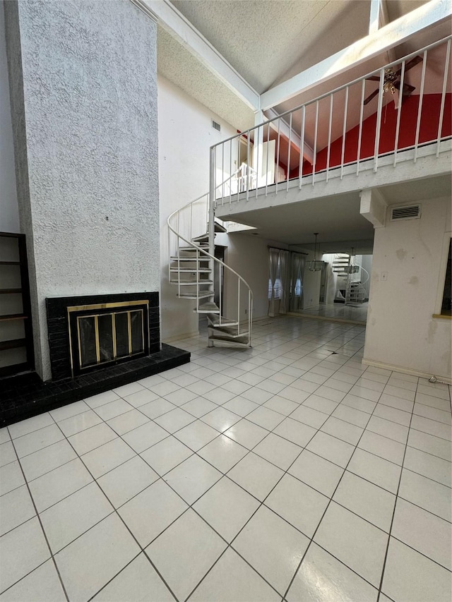 interior space featuring ceiling fan, tile patterned flooring, a towering ceiling, and a textured ceiling