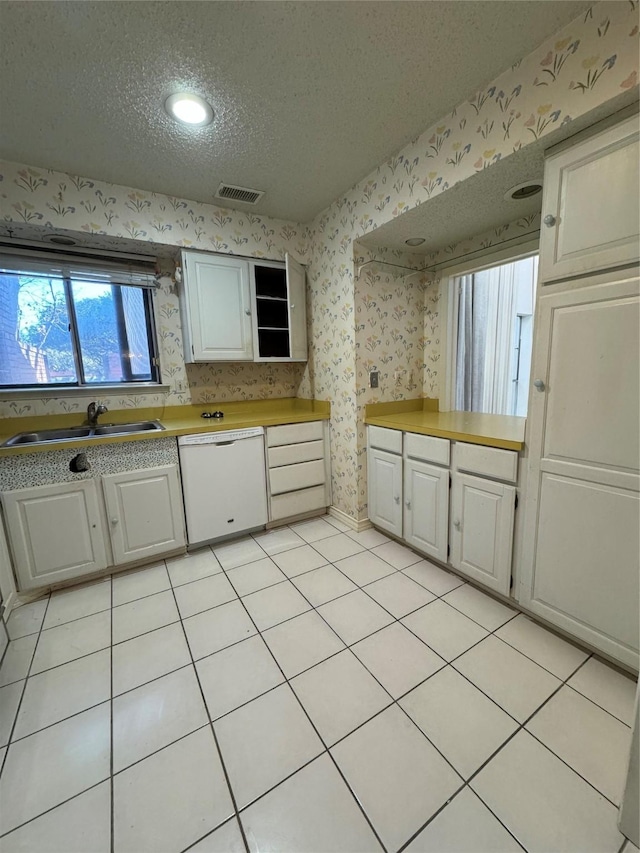 kitchen with sink, light tile patterned flooring, white dishwasher, a textured ceiling, and white cabinets