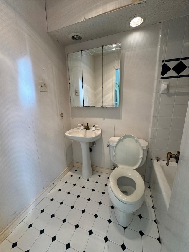 bathroom featuring toilet, a tub, and sink