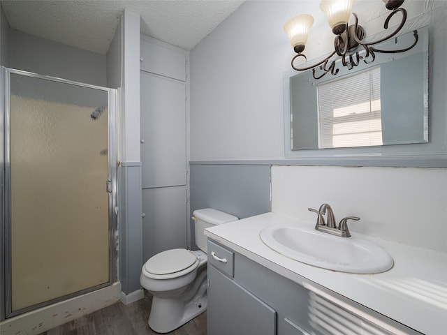 bathroom with a textured ceiling, hardwood / wood-style floors, vanity, toilet, and walk in shower