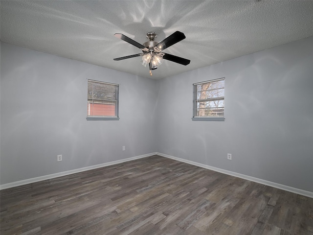 spare room featuring ceiling fan, a healthy amount of sunlight, a textured ceiling, and dark hardwood / wood-style flooring