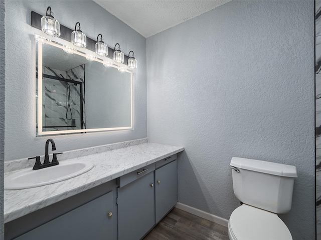 bathroom featuring hardwood / wood-style flooring, toilet, a textured ceiling, a shower with shower door, and vanity