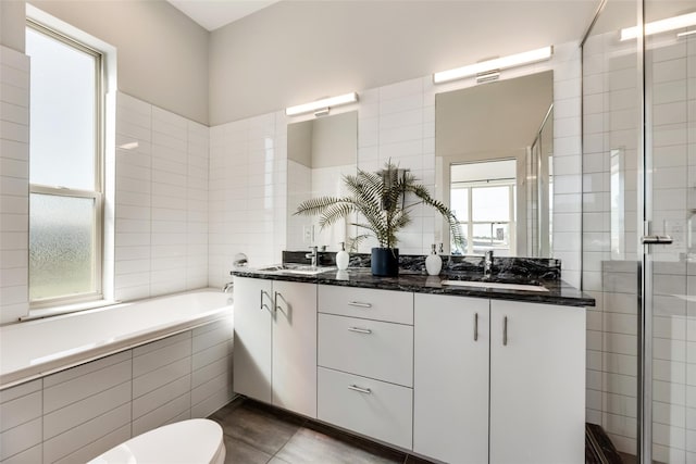 full bathroom with tile patterned floors, vanity, tile walls, shower with separate bathtub, and toilet