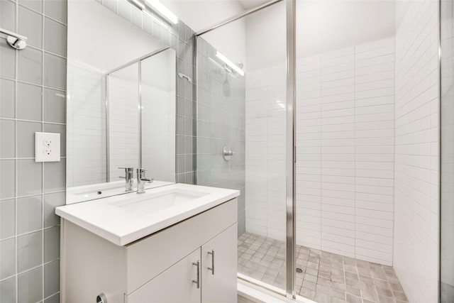 bathroom featuring a shower with door, vanity, and tile walls