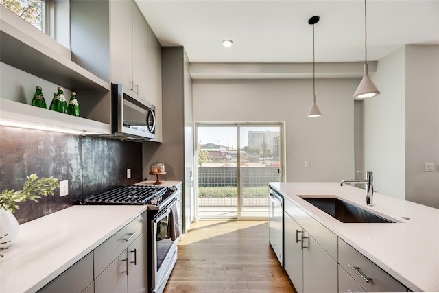 kitchen featuring gray cabinetry, sink, hanging light fixtures, backsplash, and appliances with stainless steel finishes