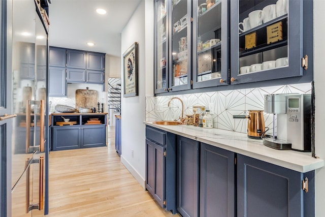 bar featuring light hardwood / wood-style floors and blue cabinets