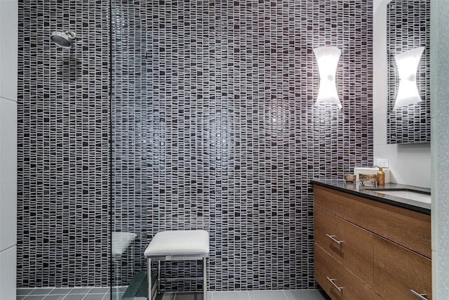 bathroom featuring tile patterned flooring, vanity, tile walls, and a shower with shower door