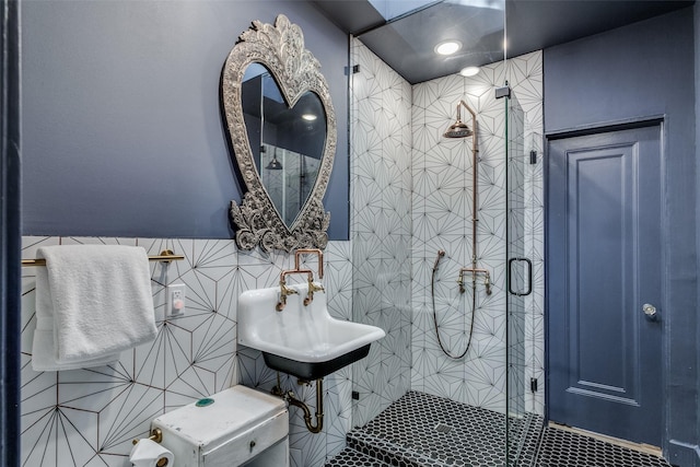 bathroom featuring sink, a shower with door, and tile walls