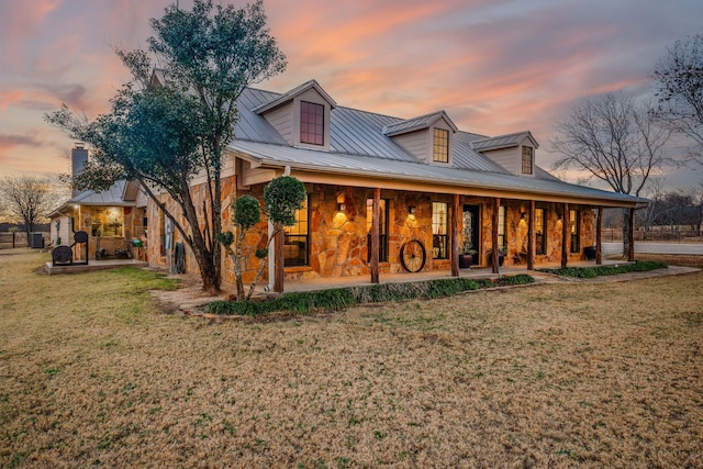 back house at dusk featuring a yard and covered porch