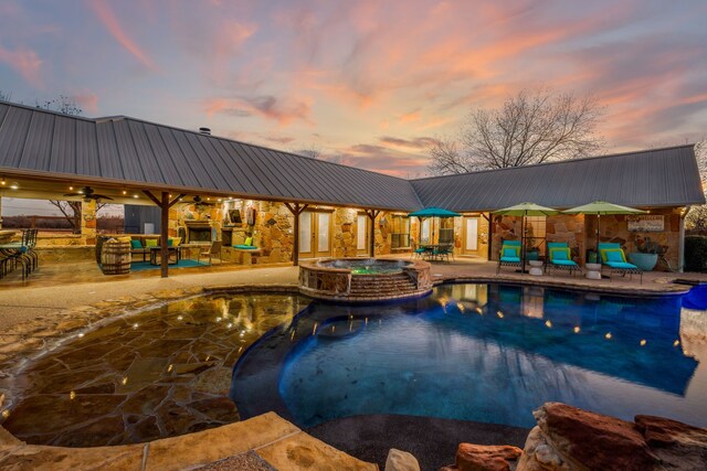 pool at dusk featuring a patio area, an in ground hot tub, and ceiling fan