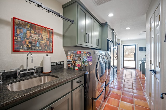 laundry area featuring cabinets, tile patterned floors, sink, separate washer and dryer, and a textured ceiling