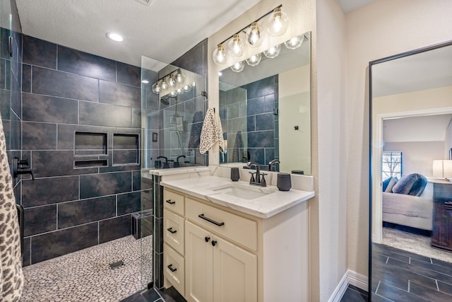 bathroom featuring vanity, tiled shower, and a textured ceiling