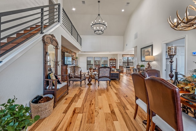 living room featuring light wood-type flooring, high vaulted ceiling, and a chandelier