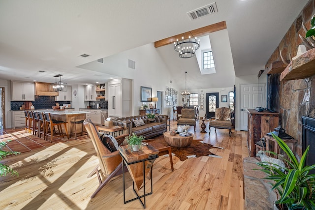 living room featuring an inviting chandelier, high vaulted ceiling, and light hardwood / wood-style flooring