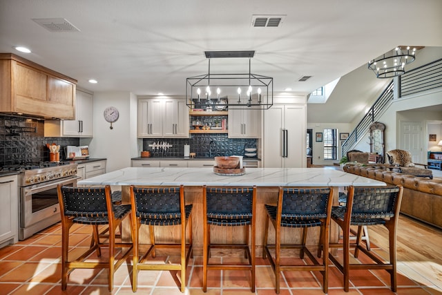 kitchen with pendant lighting, an inviting chandelier, high end stainless steel range oven, and a kitchen island