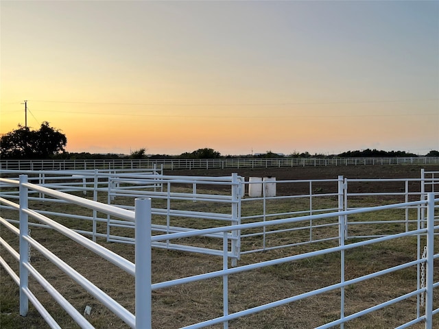 yard at dusk featuring an outbuilding and a rural view