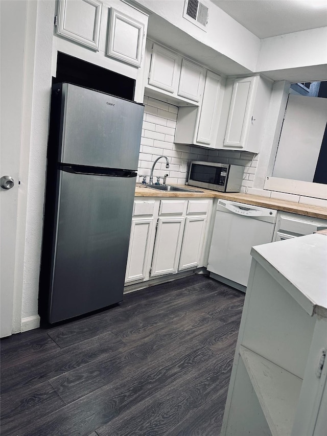 kitchen featuring white cabinets, sink, appliances with stainless steel finishes, dark hardwood / wood-style flooring, and kitchen peninsula