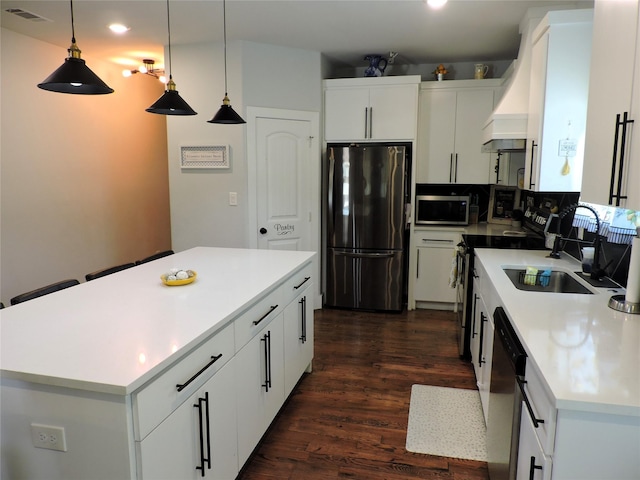 kitchen with a kitchen island, white cabinets, decorative light fixtures, and appliances with stainless steel finishes