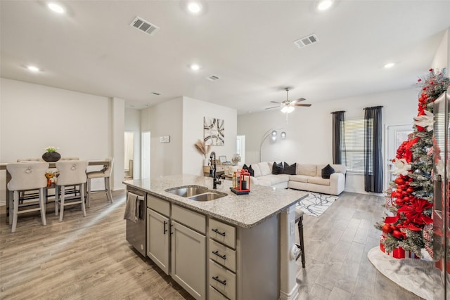 kitchen featuring gray cabinetry, a center island with sink, sink, ceiling fan, and light wood-type flooring