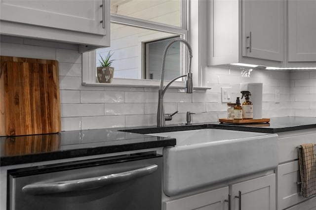 kitchen with white cabinetry, stainless steel dishwasher, tasteful backsplash, and sink