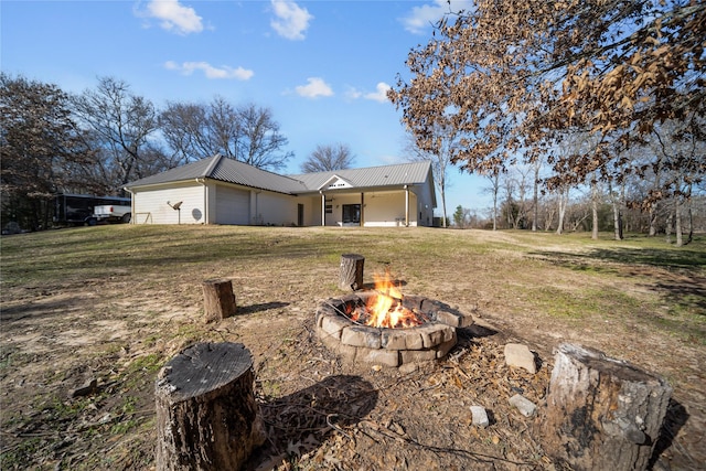 back of property with an outdoor fire pit and a lawn