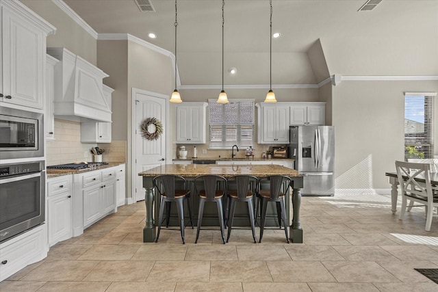 kitchen with white cabinetry, a center island, stainless steel appliances, premium range hood, and stone countertops