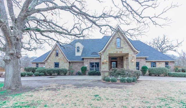 view of front of home featuring a shingled roof, stone siding, and brick siding