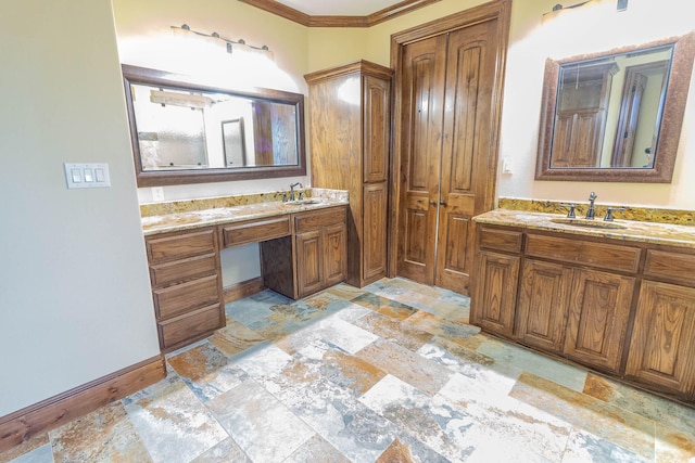 bathroom featuring stone finish floor, two vanities, a sink, and baseboards